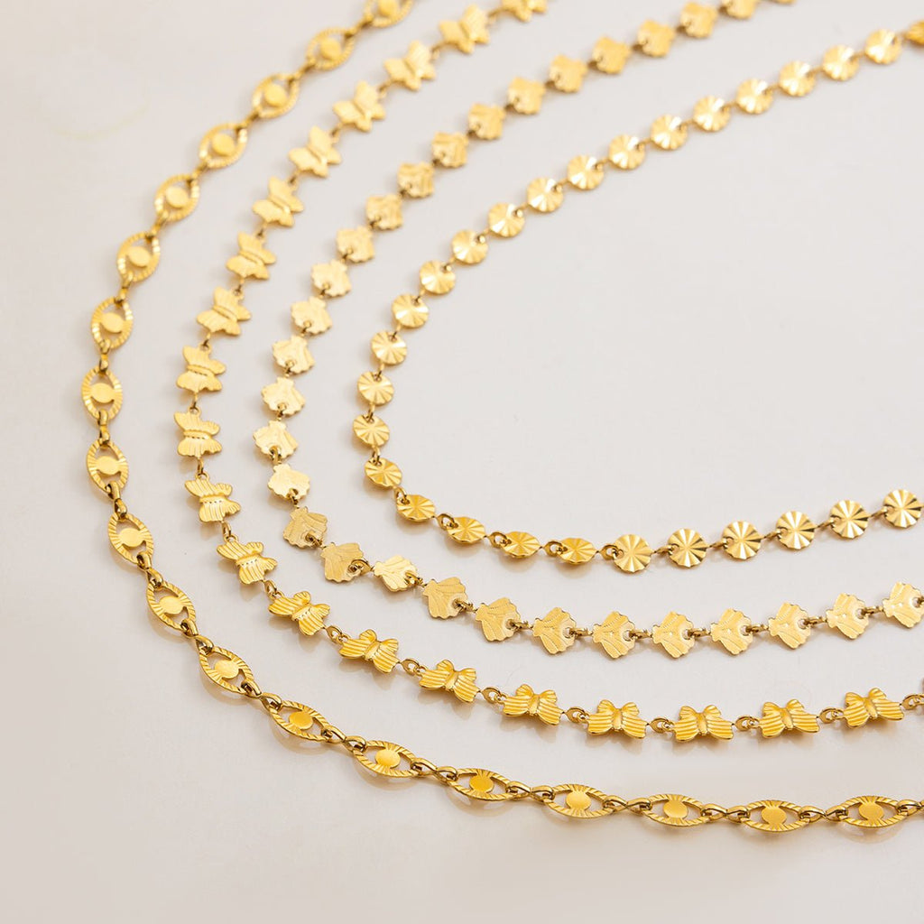 Three gold chains of different designs on a light gray background