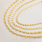 Three gold chains of different designs on a light gray background