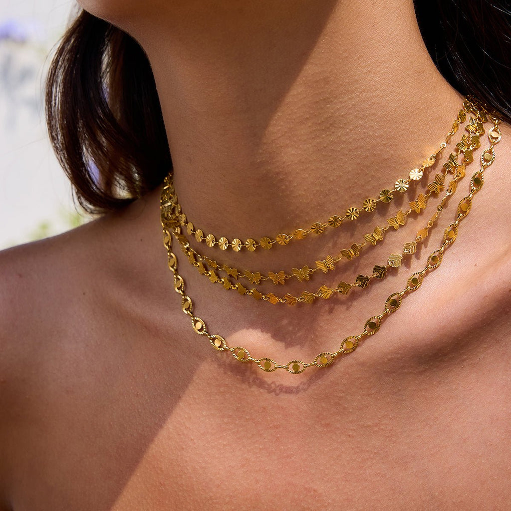 Close-up of a person wearing two gold necklaces with a blurred background