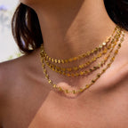 Close-up of a person wearing two gold necklaces with a blurred background