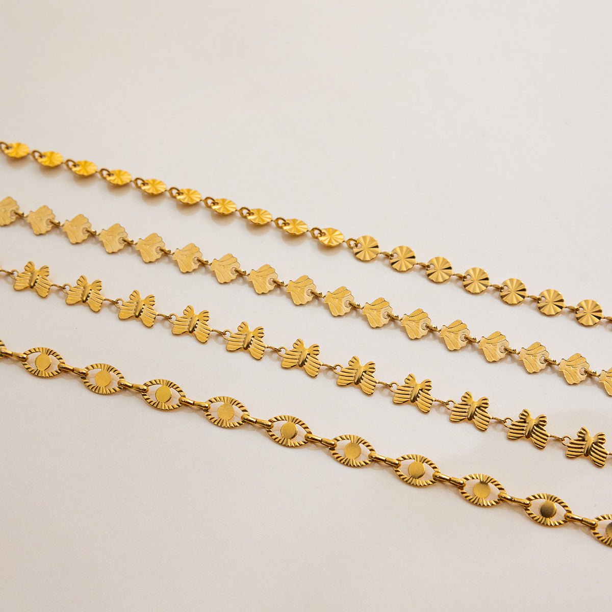 Three gold chains of different designs on a light gray background