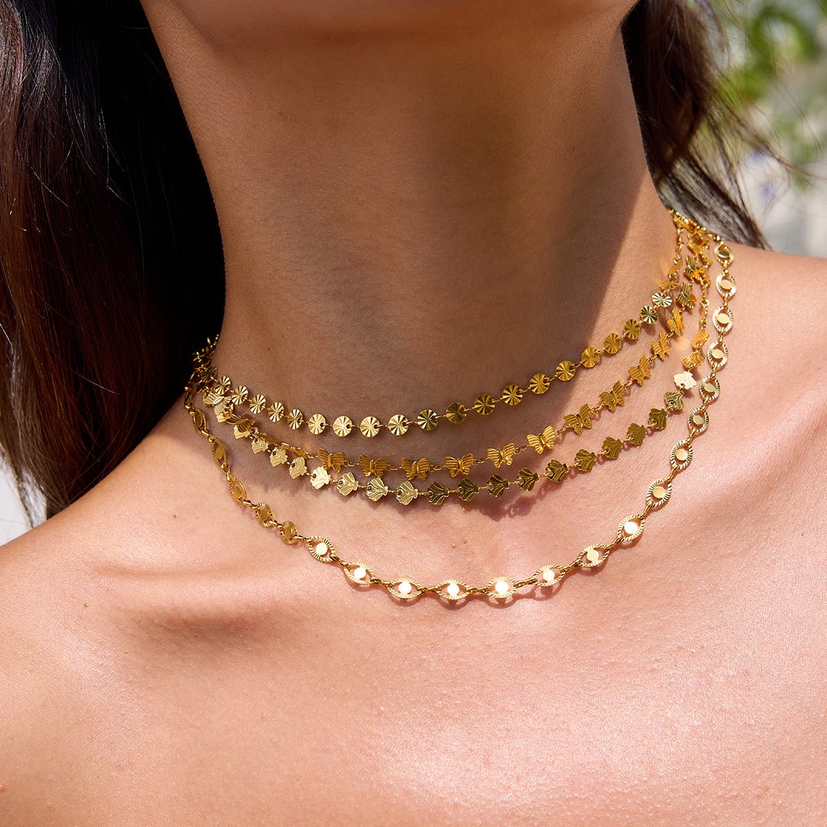 Close-up of a person wearing two gold necklaces with a blurred background