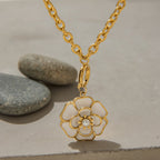 Gold necklace with a floral pendant on a neutral background