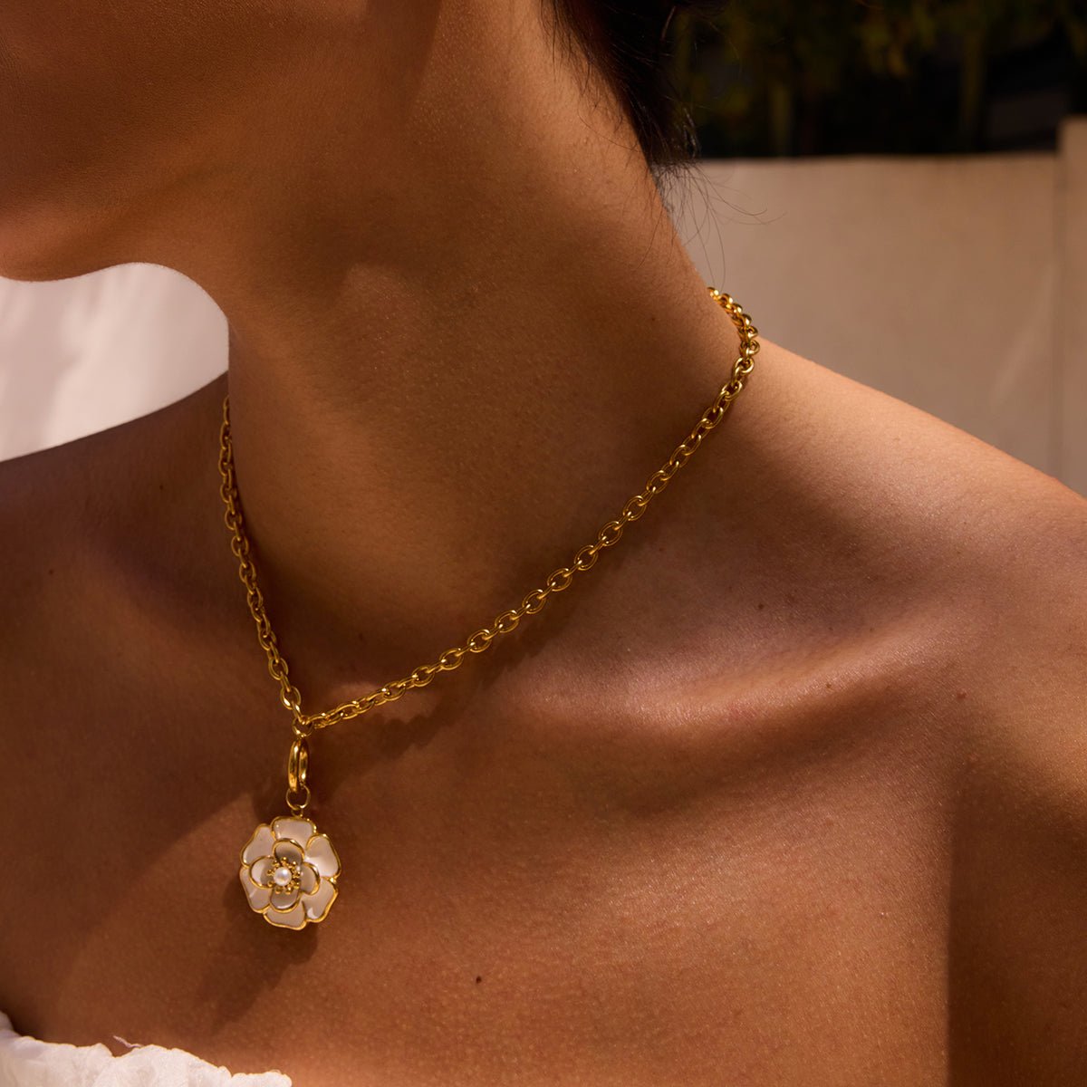 Gold necklace with a floral pendant on a person's neck