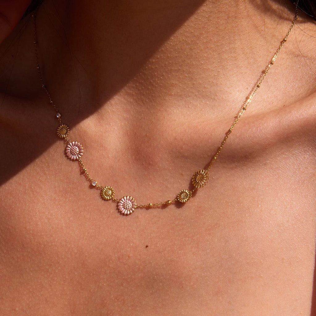 Gold necklace with floral pendants on a person's neck