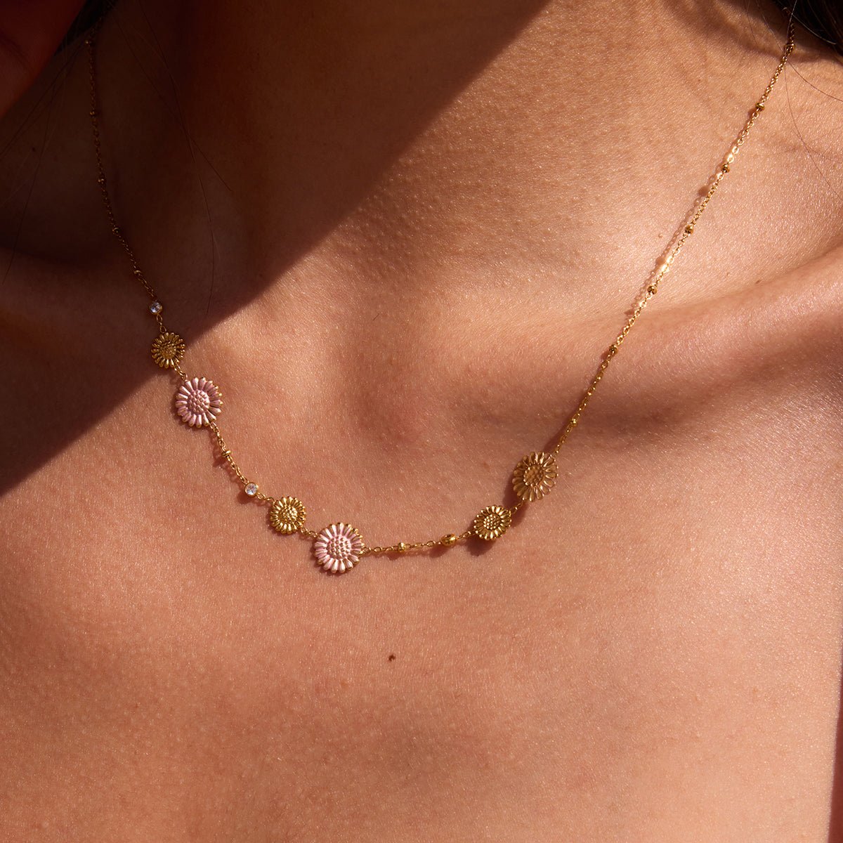 Gold necklace with floral pendants on a person's neck