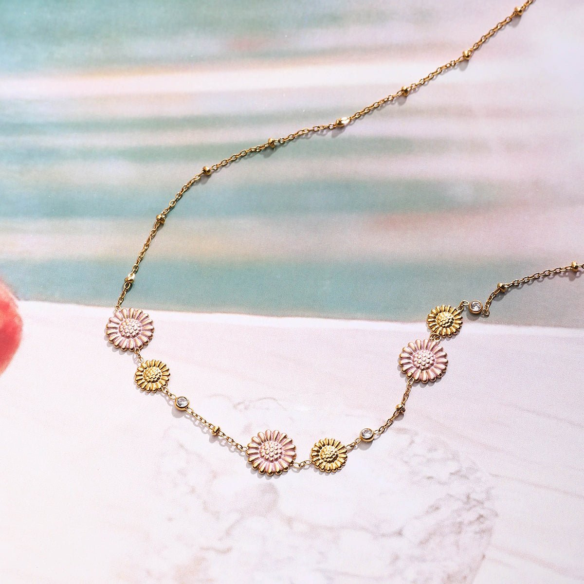 Gold necklace with sunflower-shaped pendants on a light background