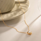 Gold necklace with a pearl pendant on a neutral background