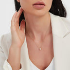 Woman wearing a delicate necklace with a pearl pendant on a white background