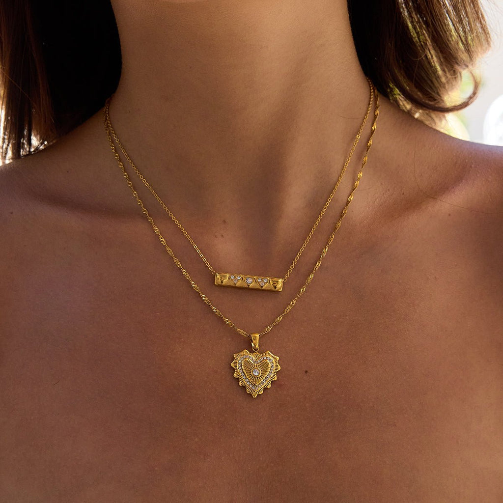 Gold necklace with a heart-shaped pendant on a person's neck
