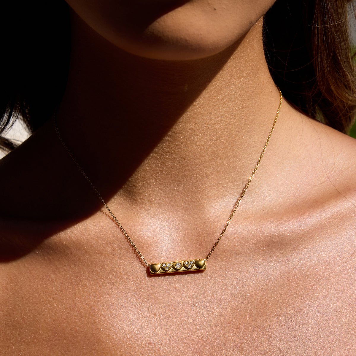 Gold necklace with heart-shaped pendants on a person's neck