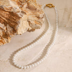 Pearl necklace with a gold clasp on a textured beige surface