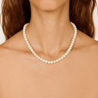 Pearl necklace worn by a person with a neutral background