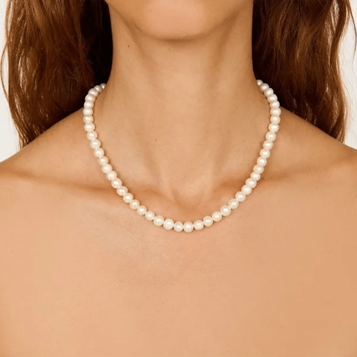 Pearl necklace worn by a person with a neutral background