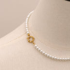 Pearl necklace with a gold clasp on a mannequin bust.