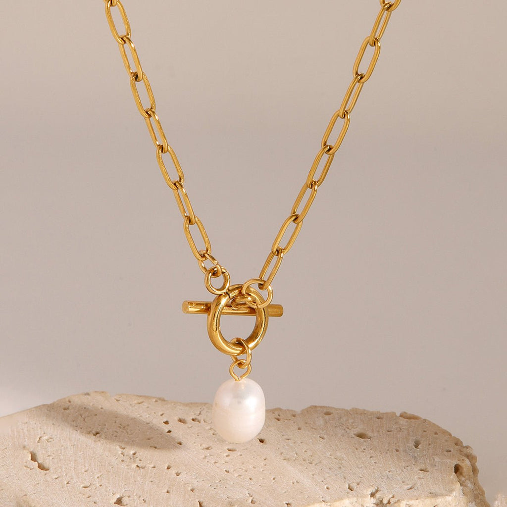 Gold necklace with a pearl pendant on a beige background