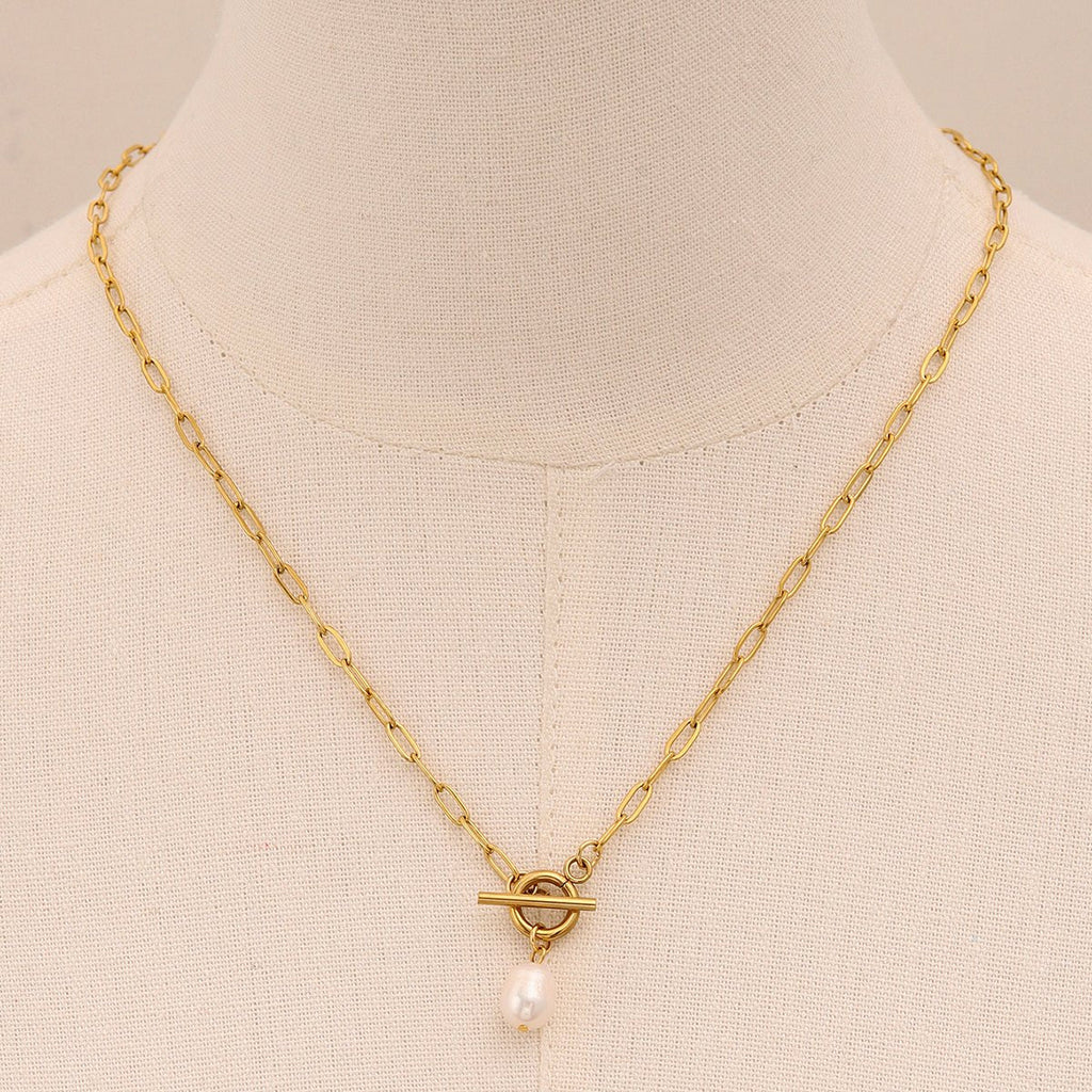 Gold necklace with a pearl pendant on a mannequin bust.