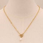 Gold necklace with a pearl pendant on a mannequin bust.