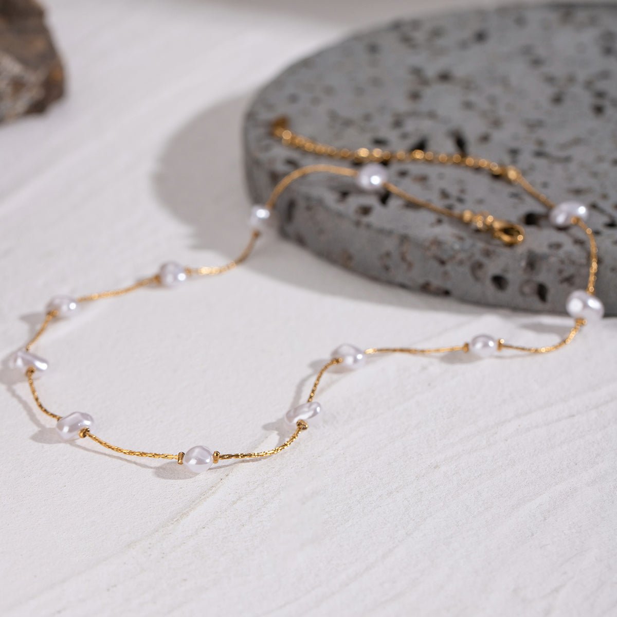 Gold necklace with pearls on a textured surface