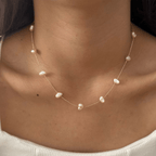 Pearl necklace on a person wearing a white top