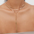 Gold body chain worn by a person on a neutral background