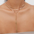 Gold body chain worn by a person on a neutral background