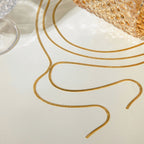 Gold earring wires on a white surface with a textured gold object in the background