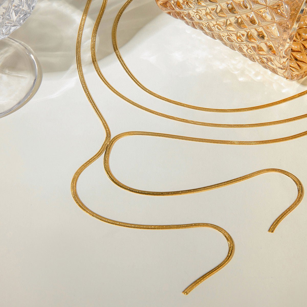 Gold earring wires on a white surface with a textured gold object in the background