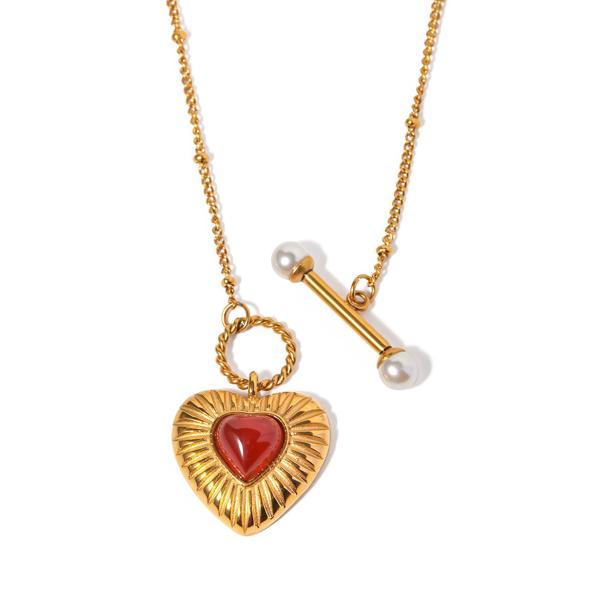 Gold necklace with a heart-shaped pendant featuring a red stone on a white background