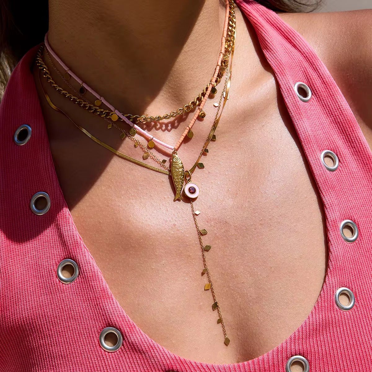 Close-up of a person wearing a gold necklace with a pink top.