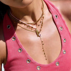 Close-up of a person wearing a gold necklace with a pink top.