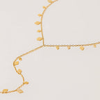 Gold necklace with small heart pendants on a light beige background