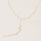 Gold necklace with leaf-shaped pendants on a light beige background