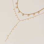 Two gold necklaces with small beads on a beige background