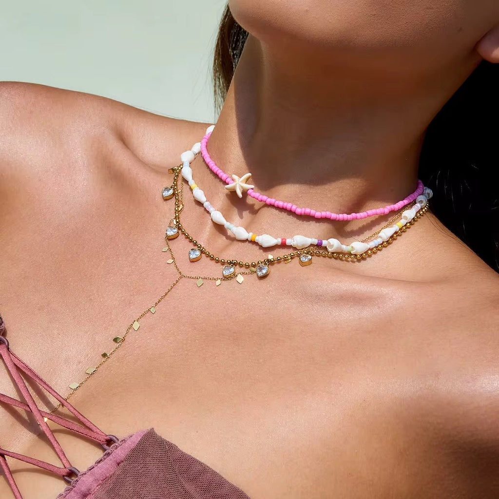 Close-up of a woman's neck wearing multiple necklaces with a blurred background