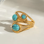 Gold ring with turquoise stones on a white background