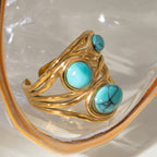Gold ring with turquoise stones on a white background