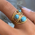 Gold ring with turquoise stones on a finger
