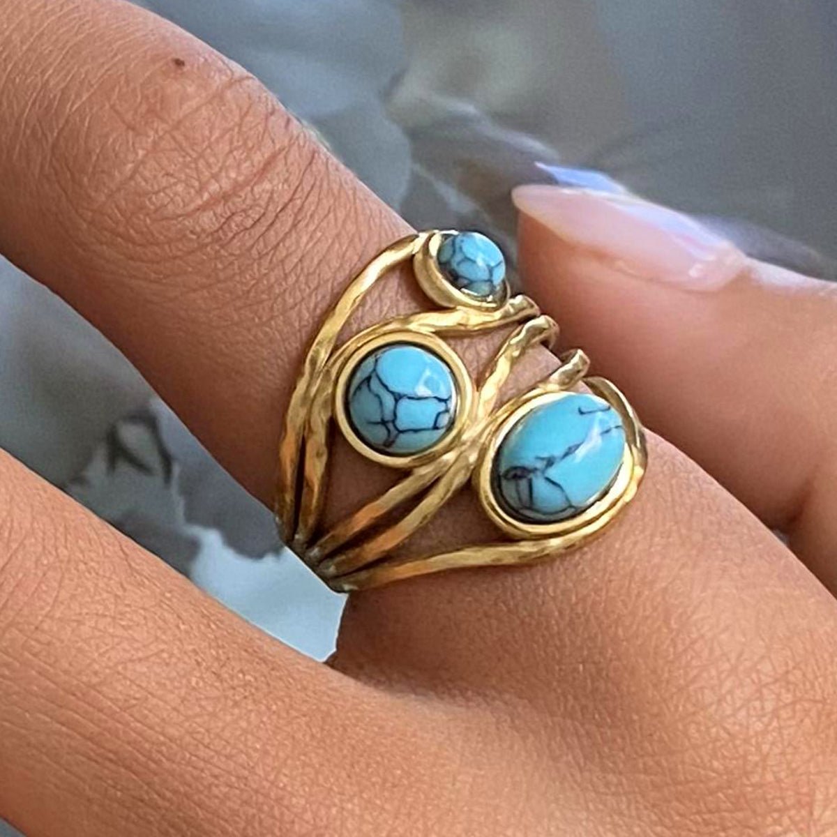 Gold ring with turquoise stones on a finger