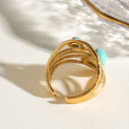 Gold ring with turquoise stones on a light background