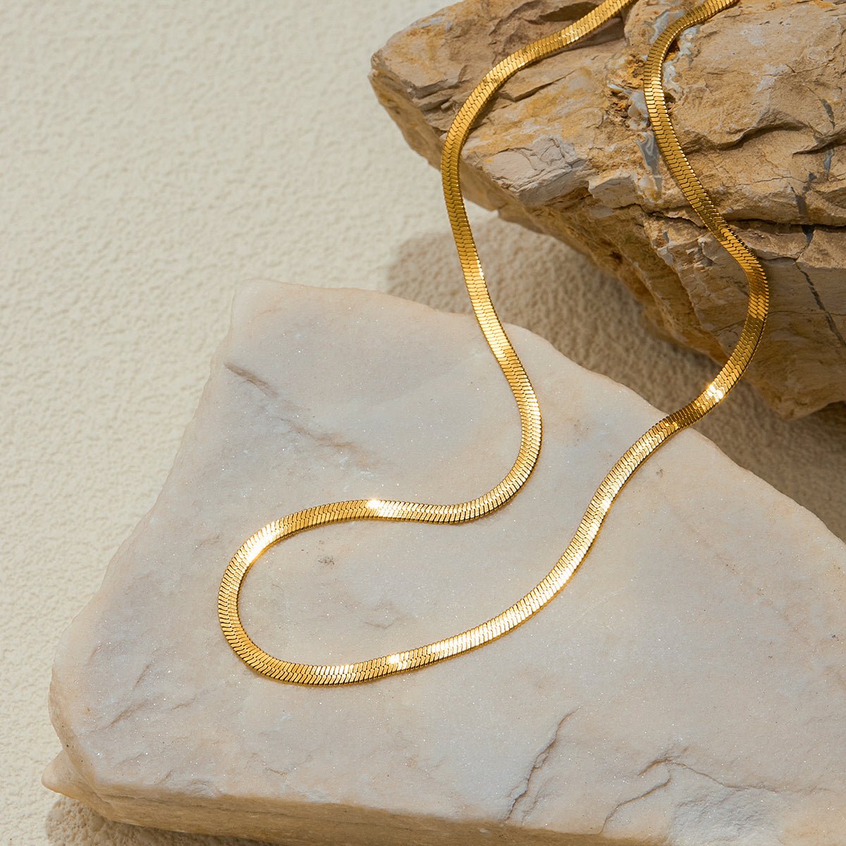 Gold necklace on a textured stone surface