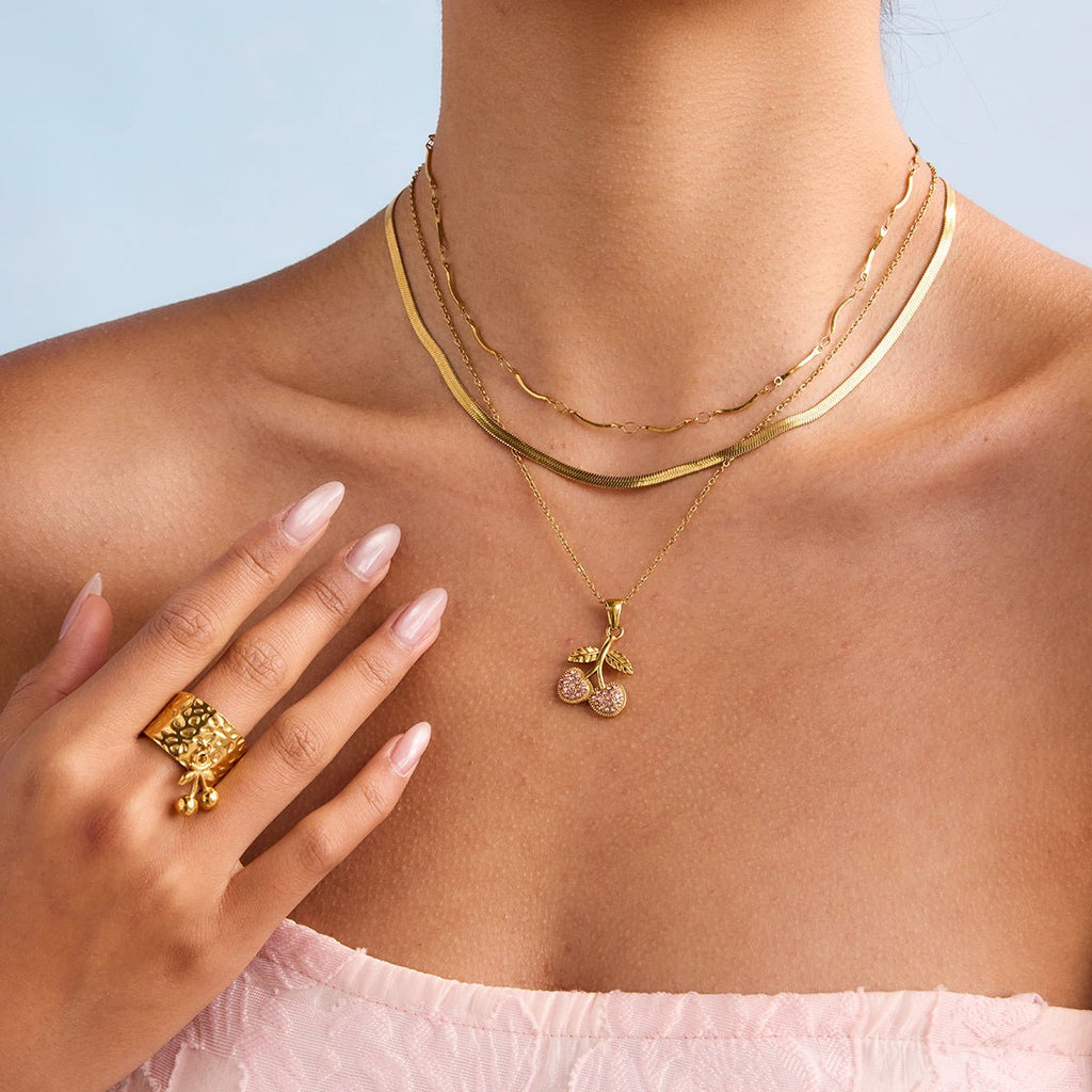 Gold necklaces and ring on a person against a light blue background