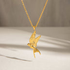 Gold bird pendant necklace on a neutral background