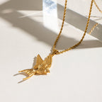Gold bird-shaped pendant necklace on a light background
