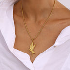 Gold bird-shaped pendant necklace on a person wearing a white shirt.