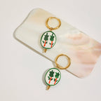 Two keychains with green designs on a white surface