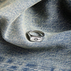 Silver ring with a sun design on blue denim fabric