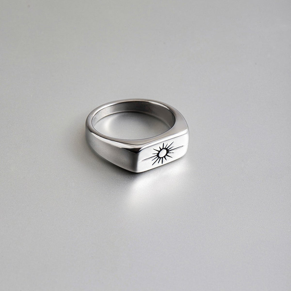 Silver ring with a sun emblem on a gray background
