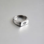 Silver ring with a sun emblem on a gray background