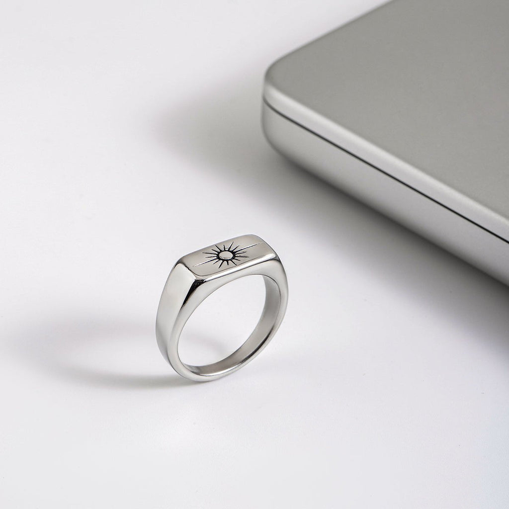 Silver ring with engraved design on a light gray surface
